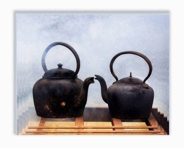 two old cast iron kettles, their strop's almost touching as in a kiss, smoky background