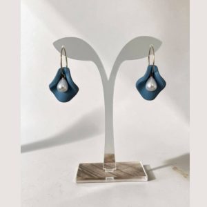 Handmade blue clay petal earrings with pearl drops on a display stand.